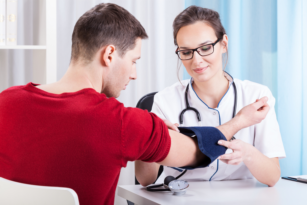 Doctor measuring blood pressure of young man